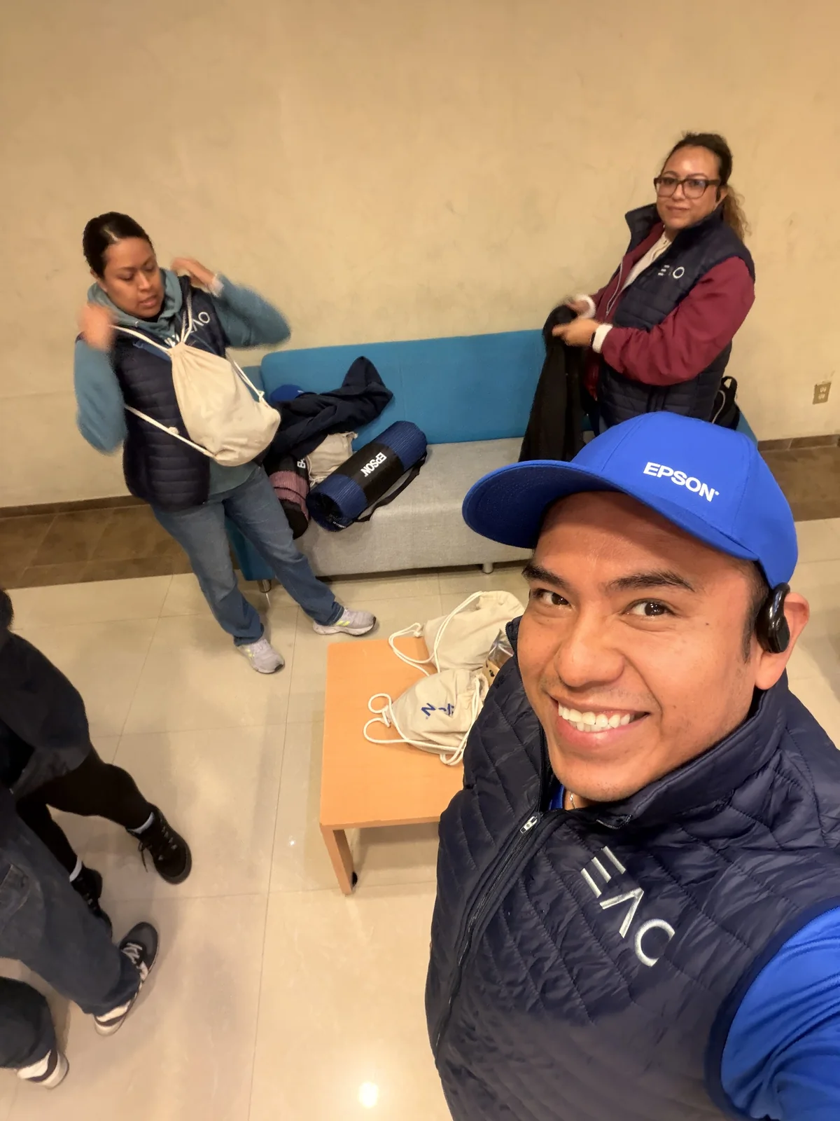 Selfie del equipo de Epson Empresas con gorras Epson y chalecos EAO en el vestíbulo, antes de subir al camión