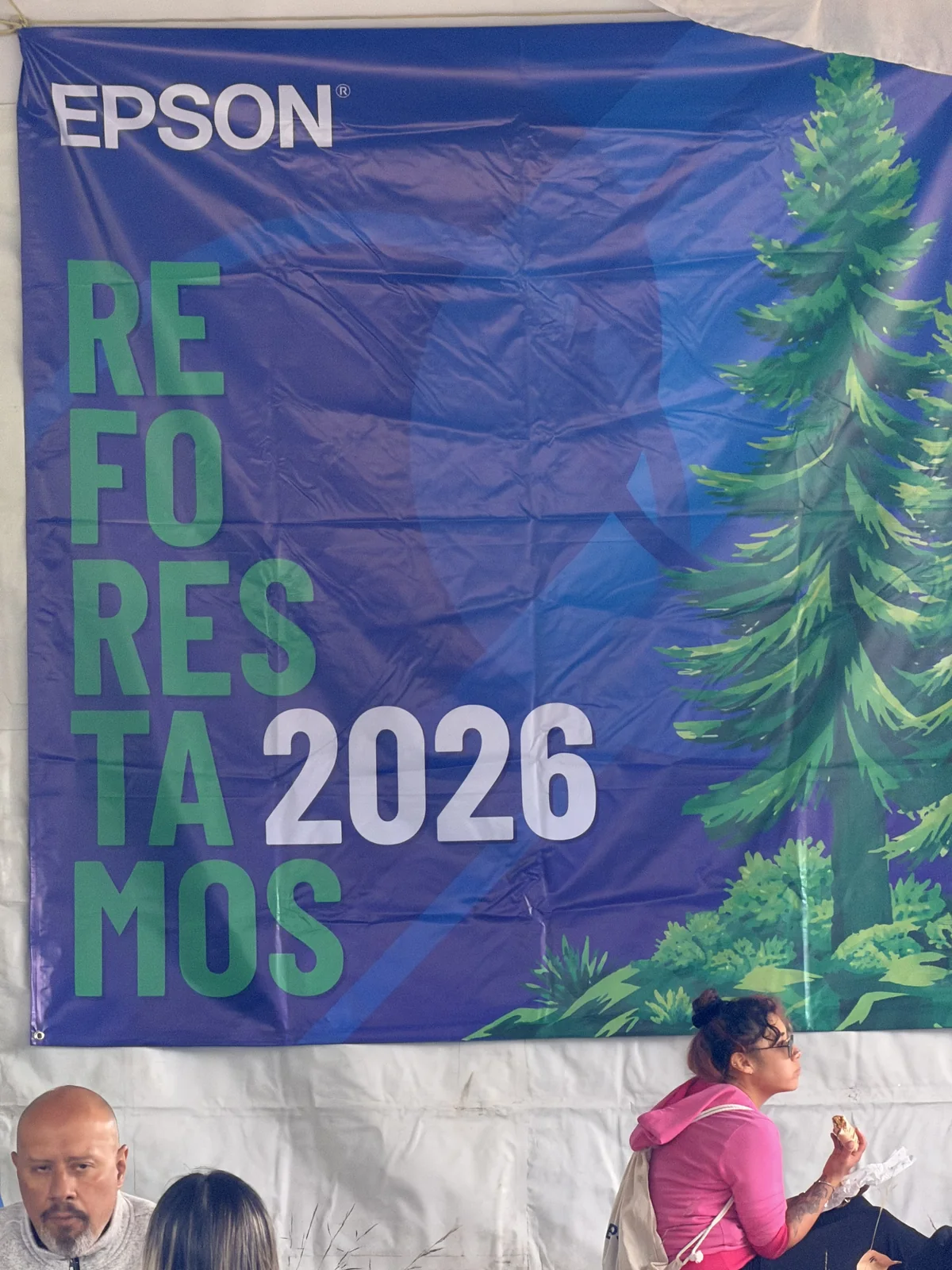 Lona de Epson con la leyenda «Reforestamos 2026» colgada dentro de la carpa del campamento base