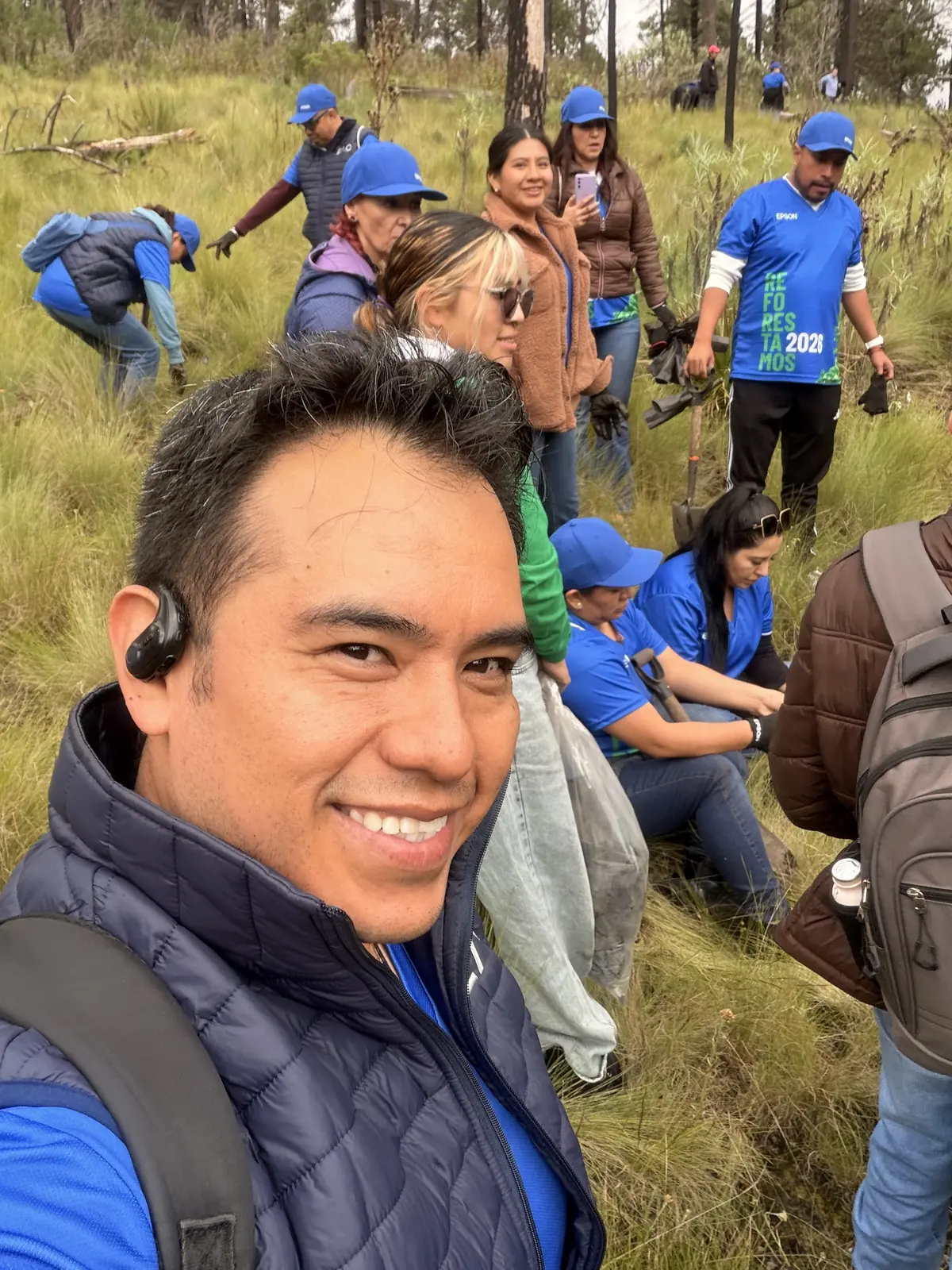 Selfie del equipo de Epson Empresas en el pastizal, con gorras y camisetas azules, sonriendo después de plantar